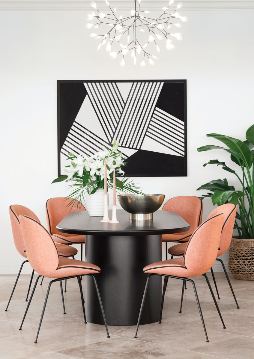 In the dining area, shapely Gubi “Beetle” chairs in an Osborne & Little terracotta wool encircle the ebony stained oak table in geometric contrast to the black-and-white abstract by artist Jaime Derringer via Minted.