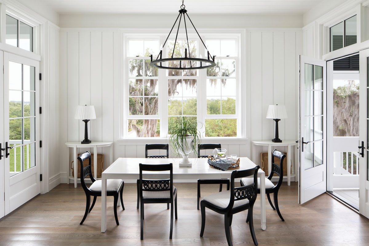 Cascading sunlight floods the breakfast room through unadorned windows that frame picturesque views. Capitol Lighting’s iron ring chandelier is paired with an eclectic array of period furnishings while remaining true to the understated monochromatic palette.