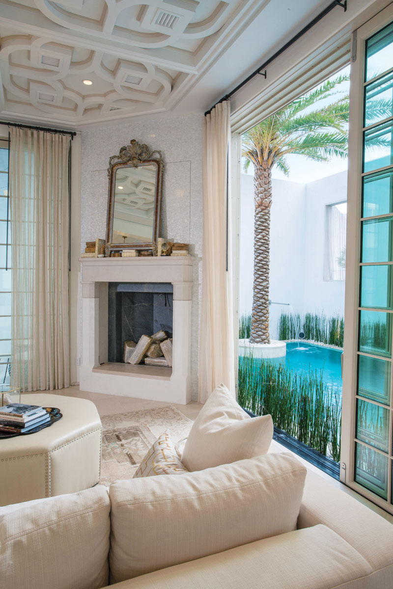 A French mirror, circa 1800s, and turn-of-the-century Italian theatre urns adorn the fireplace. Steps away, glass doors slide open to the floating pavilion on one side and the pool on the other.