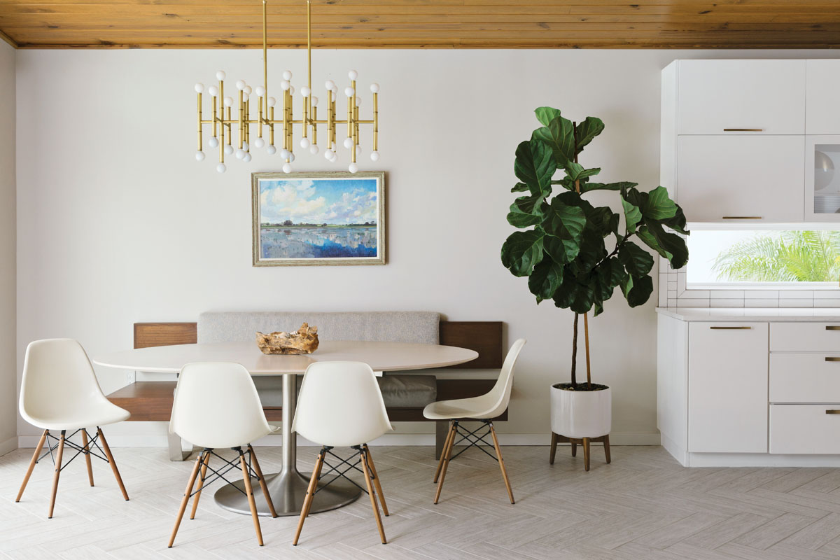 Eames fiberglass chairs circle Saarinen’s oval dining table in the casual breakfast area, where a custom banquette fabricated by Stettinius Construction appears to float next to S&W Kitchen Supply’s sleek, white cabinetry.