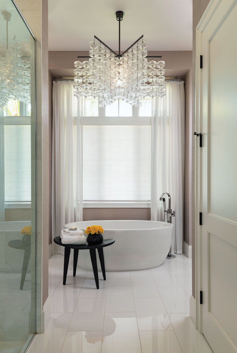 A heavenly chandelier made from glass globes is the focal point in the serene master bath, where Liegeois kept everything clean, simple, and spa-like from the fixtures to the palette.