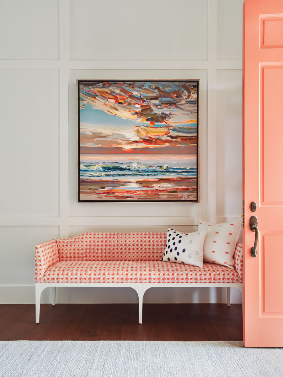 Architectural molding details were added to a new wall that creates a more defined foyer. A Thibaut settee covered in coral fabric complements the bold front door.