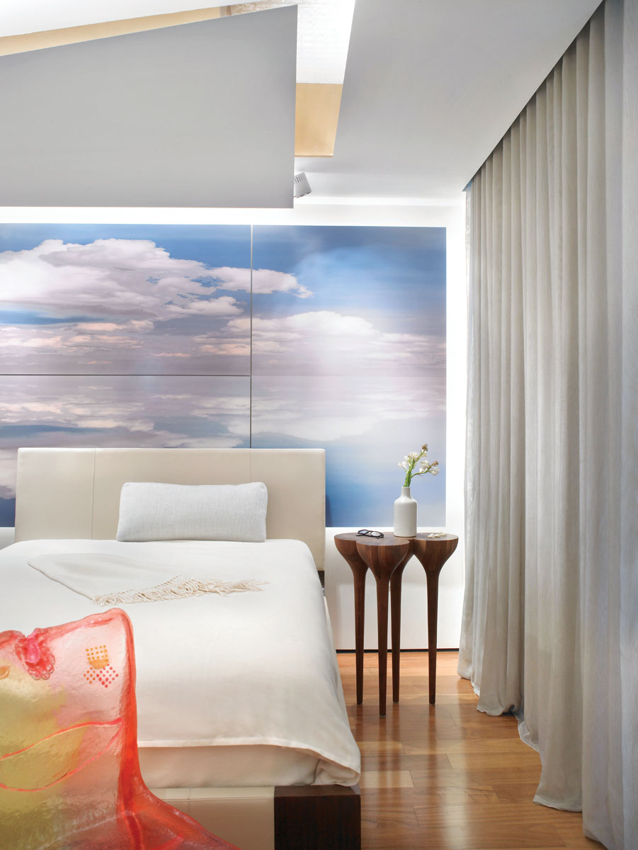 The guest bedroom has a heavenly essence thanks to the cloud photograph printed on aluminum (a Glottman original) and the gold leaf on the ceiling. The original room had a tray ceiling, so Glottman introduced a more sculptural intervention by creating floating planes that reference clouds.