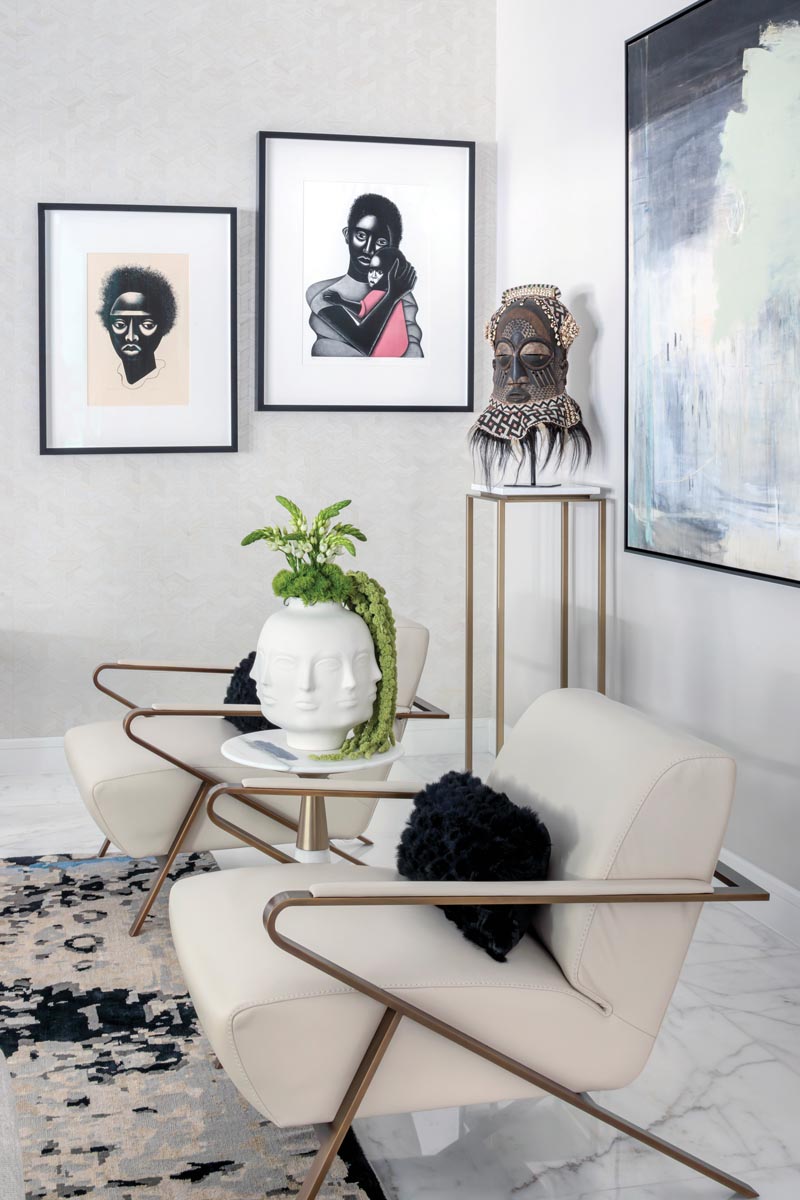 A pair of sculptural chairs from American Leather composes an artful moment in the great room. A Kuba Kete mask from the Democratic Republic of Congo and two graphic works by Elizabeth Catlett punctuate the vignette.