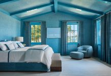 The primary suite is saturated in blue with Dedar drapes, an Armani/Casa wallcovering, and a bed, club chair, and ottoman by Holly Hunt. The taupe Rosenfeld area rug complements the white oak floor.