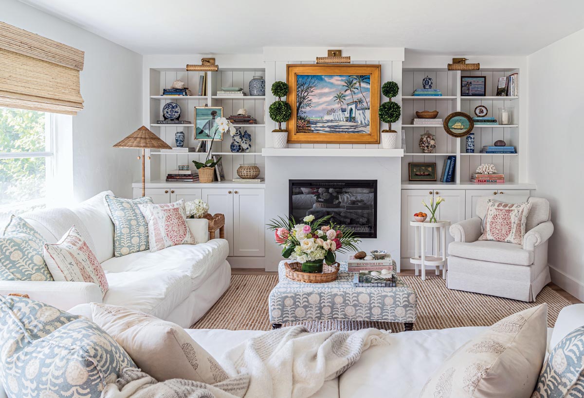 Books, sea treasures, porcelain ceramics, and vintage decor line the built-in shelves in the living room. The Paul Arsenault painting above the mantle provided some inspiration for the home’s color palette, including the Penny Morrison block print textiles found throughout the room.