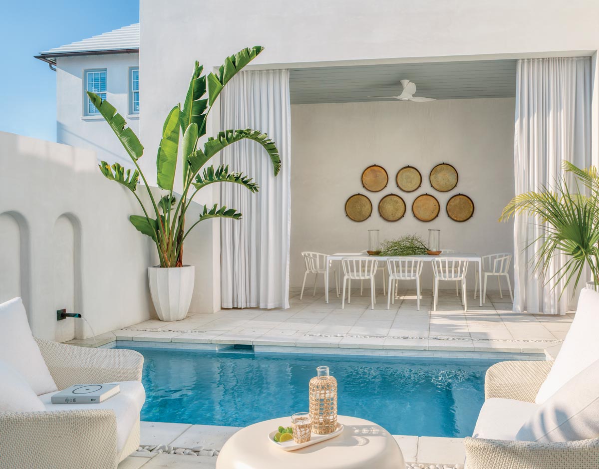 Vintage Moroccan brass trays bring texture to the outdoor dining alcove. The curtains around the dining area soften the afternoon sun, but they’re mostly there to provide ambiance. Poolside wicker furniture from JANUS et Cie next to the splash pool adds to the boutique resort feel of the area.