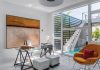 A corner office merges with the pool patio, creating an upbeat, sun-drenched workspace. Knoll’s orange Womb chair echoes the warm hues in an oil painting by Buddhi Solowenta VanRoos.
