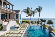 Showcasing panoramic views of Sarasota Bay, the home’s impressive resort-style pool patio and its pristine tiered yard often slow down the passing boat traffic. Custom pavers with grass strips woven in between define the landscape, while decorative planters mark the waterside edge of the pool.