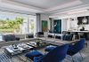 The great room prioritizes sweeping panoramic views of the native landscape along with the property’s water features. Centered beneath a floating reversed-soffit ceiling feature, Roche Bobois’ ultra-modern furnishings generate a chic French vibe.