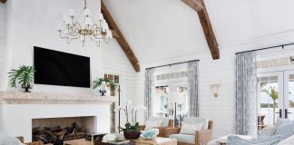 The living room’s ceiling wood beams are reclaimed from old Ohio barns. The soaring, 72-inch-wide fireplace is paired with a hand-carved coral mantle. Furniture here includes lounge chairs by Palecek, draperies by Quadrille, and an area rug by Stark. The coffee tables are from the homeowners’ previous residence.