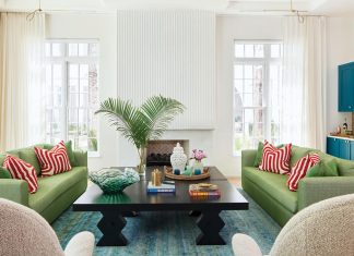 In the main living room, interior designer Catherine Christie-Zanghi paired spring green-hued sofas with patterned persimmon pillows. The soft, rounded forms bring warmth against cream walls. A bold bar, reimagined in a pop of blue, stands apart in the open plan, while French cast panels clad the fireplace and echo the home’s sculptural, artful detailing.