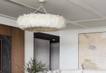 Bold accents, including a Palecek chandelier, Vanguard Furniture ottoman, and Arteriors cocktail table, provide a punch to the mostly white living area. Esposito used natural elements—like wood, stone, coco shells, and leather—to give the room a timeless quality.