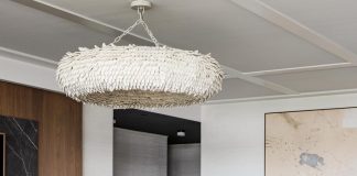 Bold accents, including a Palecek chandelier, Vanguard Furniture ottoman, and Arteriors cocktail table, provide a punch to the mostly white living area. Esposito used natural elements—like wood, stone, coco shells, and leather—to give the room a timeless quality.