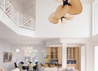 In the home’s two-story great room, clever style touches include fringe trim on the Vanguard Furniture sofas, bright pink fabric upholstery on the club chairs, and a lattice pattern on the pillows that recalls the design of the upstairs railing.