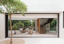 Divided by a floating staircase, the great room opens on three sides, dissolving the boundary between inside and out. The home’s sliding glass walls open fully to connect the interior spaces to the surrounding outdoor areas.