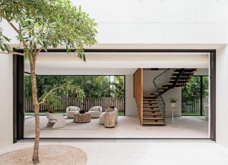 Divided by a floating staircase, the great room opens on three sides, dissolving the boundary between inside and out. The home’s sliding glass walls open fully to connect the interior spaces to the surrounding outdoor areas.
