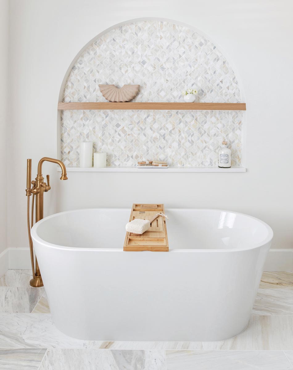 To backdrop the tub in the primary bathroom, an arched architectural niche was created to serve as both a focal point in the room and a showcase for decor and bath products.
